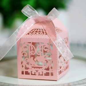 Macro detail of laser-cut lovebird candy box in pale pink pearlescent paper with ribbon