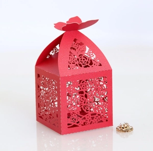Detail of red laser-cut wedding favor box with rose patterns and butterfly closure