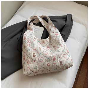 Detail of white textured tote bag featuring pink bear and strawberry patterns on quilted fabric