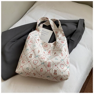 Close-up of quilted tote bag with cute bear and bow patterns on white fabric