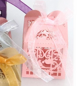 Detail of pink laser-cut wedding favor box with lovebirds and organza ribbon bow
