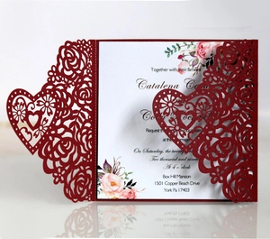 Detail of laser-cut burgundy invitation with heart and floral patterns and paper insert