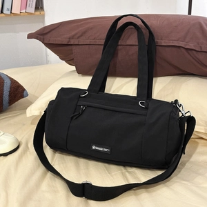 Minimalistische schwarze Zylindersporttasche mit verstellbarem Gurt auf dem Bett