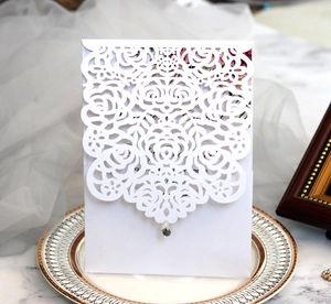 Macro detail of laser-cut floral wedding invitation with a sparkling rhinestone accent