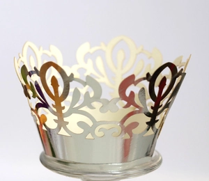 Intricate laser-cut silver crown cupcake wrappers for elegant party table decoration