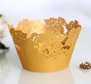 Macro detail of laser-cut gold cupcake liners with elegant grape and vine lace patterns