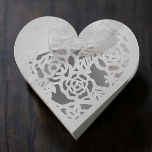 Détails de découpe laser de roses sur boîte de mariage blanche en forme de coeur avec ruban