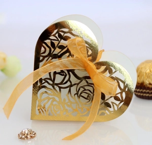 Detailed macro of golden laser-cut heart favor box with rose patterns and ribbon