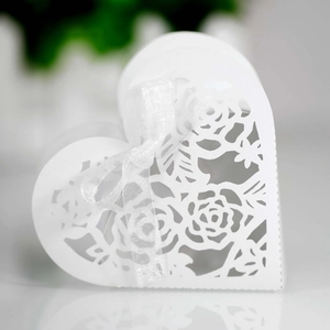 Gros plan d'une boîte à bonbons blanche en cœur avec roses découpées et ruban