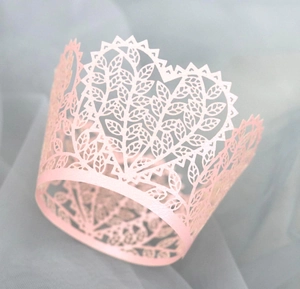 Laser-cut pink cupcake wrapper with intricate leaf pattern and pearlescent finish