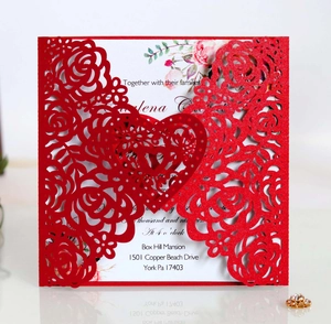Macro detail of laser-cut red heart and floral patterns on a wedding invitation card