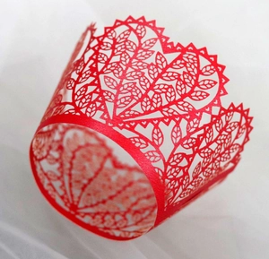 Laser cut red paper cake wrappers with intricate tree leaf patterns for wedding decor