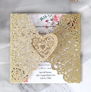 Détail macro du faire-part de mariage doré à paillettes avec découpes de cœur laser