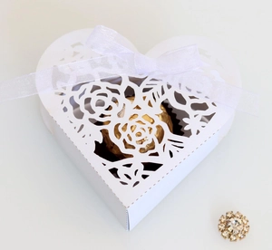 Détail de la boîte à bonbons blanche en forme de cœur avec découpes roses et ruban