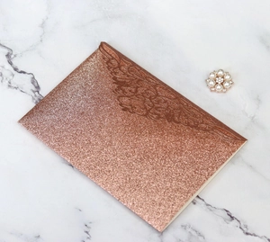 Detailed laser-cut floral pattern on rose gold glitter tri-fold wedding invitation