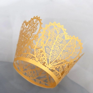 Golden laser-cut cupcake wrappers with intricate leaf patterns for party dessert table decor