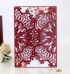 Detail of burgundy laser cut wedding invitation with intricate mandala floral patterns