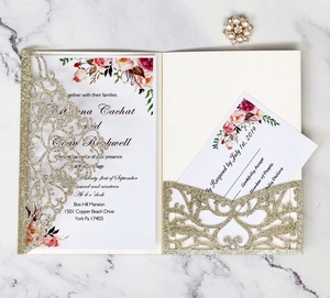 Macro detail of laser-cut gold glitter wedding invitation with floral insert on marble