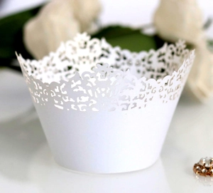 Elegant white laser-cut cupcake wrappers with intricate floral lace patterns for desserts