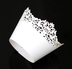 Macro detail of laser-cut white lace cupcake wrappers featuring floral hollow pattern