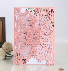 Detail of laser-cut pink wedding invitation with floral inner card and white rose deco