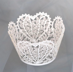Macro shot of white laser-cut cupcake wrapper with intricate heart and leaf patterns