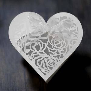 Detail of white heart laser-cut candy box with rose patterns and ribbon bow