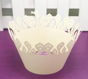 Close-up of laser-cut hollow crown pattern cupcake wrappers in cream white cardstock