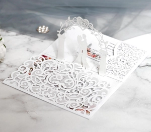 Macro view of laser-cut 3D wedding card with bride and groom silhouette in a floral arch
