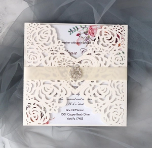 Close-up of laser-cut rose hollow invitation with heart buckle and rhinestone ribbon