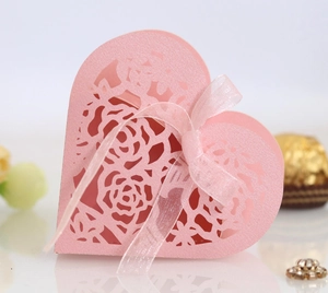 Gros plan sur une boîte à dragées cœur rose découpée au laser avec motifs de roses