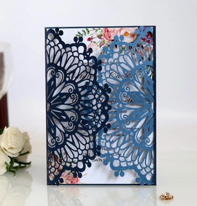 Detail of laser-cut navy blue wedding invitation with floral insert and gold rings