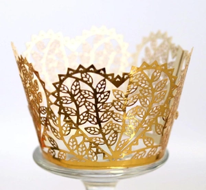 Golden laser-cut cupcake wrapper with intricate hollow leaf patterns for wedding party decor