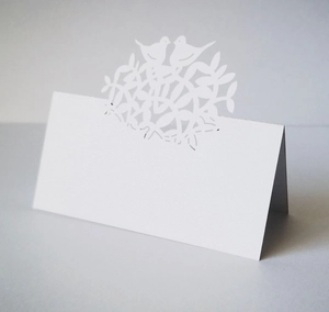 Elegant white laser-cut place card with tree of life and birds on a grey background