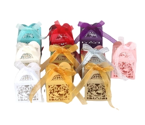 Laser-cut wedding candy boxes with intricate bird patterns and organza ribbons in various colors