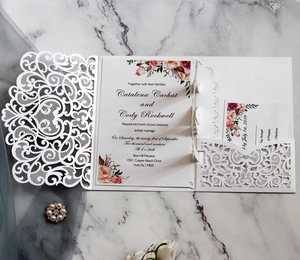 Detailed macro view of laser-cut wedding invitation with elegant lace pattern and floral card