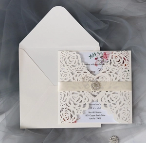 Detail of laser-cut rose hollow invitation with champagne ribbon and rhinestone buckle