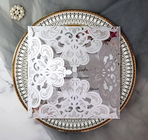Detail of laser-cut floral wedding invitation with inner card on elegant ceramic tray