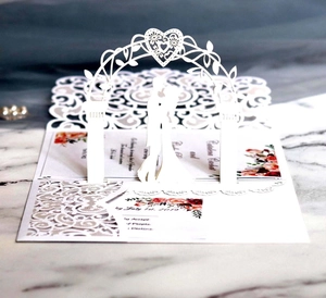 Detail of 3D laser-cut wedding invitation with floral RSVP card on marble background