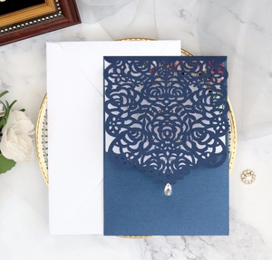 Detailed laser-cut rose design on navy blue wedding invitation with rhinestone