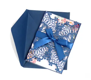 Detail of laser-cut wedding invitation with navy blue floral lace and silk ribbon bow