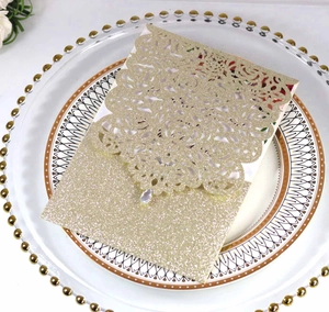 Λεπτομέρεια προσκλητηρίου γάμου laser-cut σε σαμπανιζέ χρυσό γκλίτερ με κρεμαστό κόσμημα