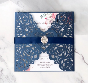 Detail of laser-cut navy blue rose invitation with white card, satin ribbon and rhinestone