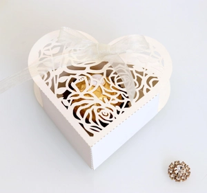 Close-up of laser-cut heart favor box with rose patterns and white satin ribbon