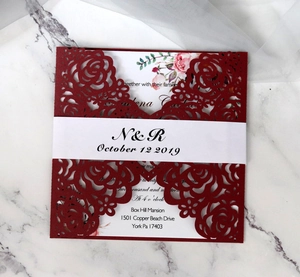 Macro detail of laser-cut burgundy flower wedding invitation with printed inner card