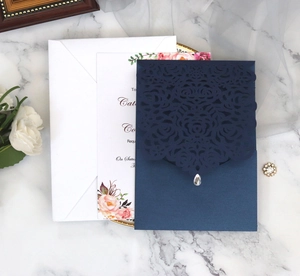 Detailed laser-cut dark blue wedding invitation set with floral inner card and white envelope