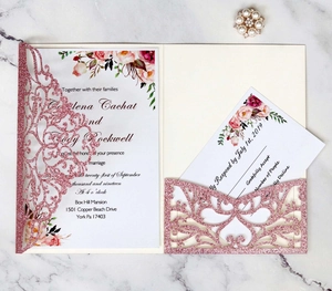 Elegant laser-cut pink glitter wedding invitation set with floral inserts on marble
