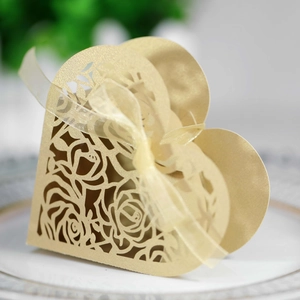 Detail of laser-cut heart favor box with golden rose pattern and elegant ribbon bow
