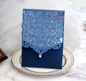 Detail of laser-cut rose hollow invitation card in navy blue with elegant waterdrop pendant