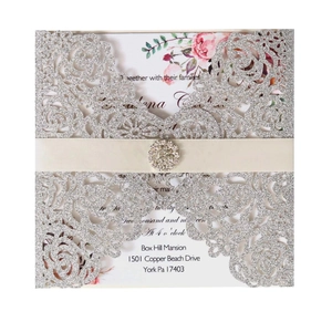 Détail d'invitation rose avec papier pailleté, ruban crème et boucle en strass